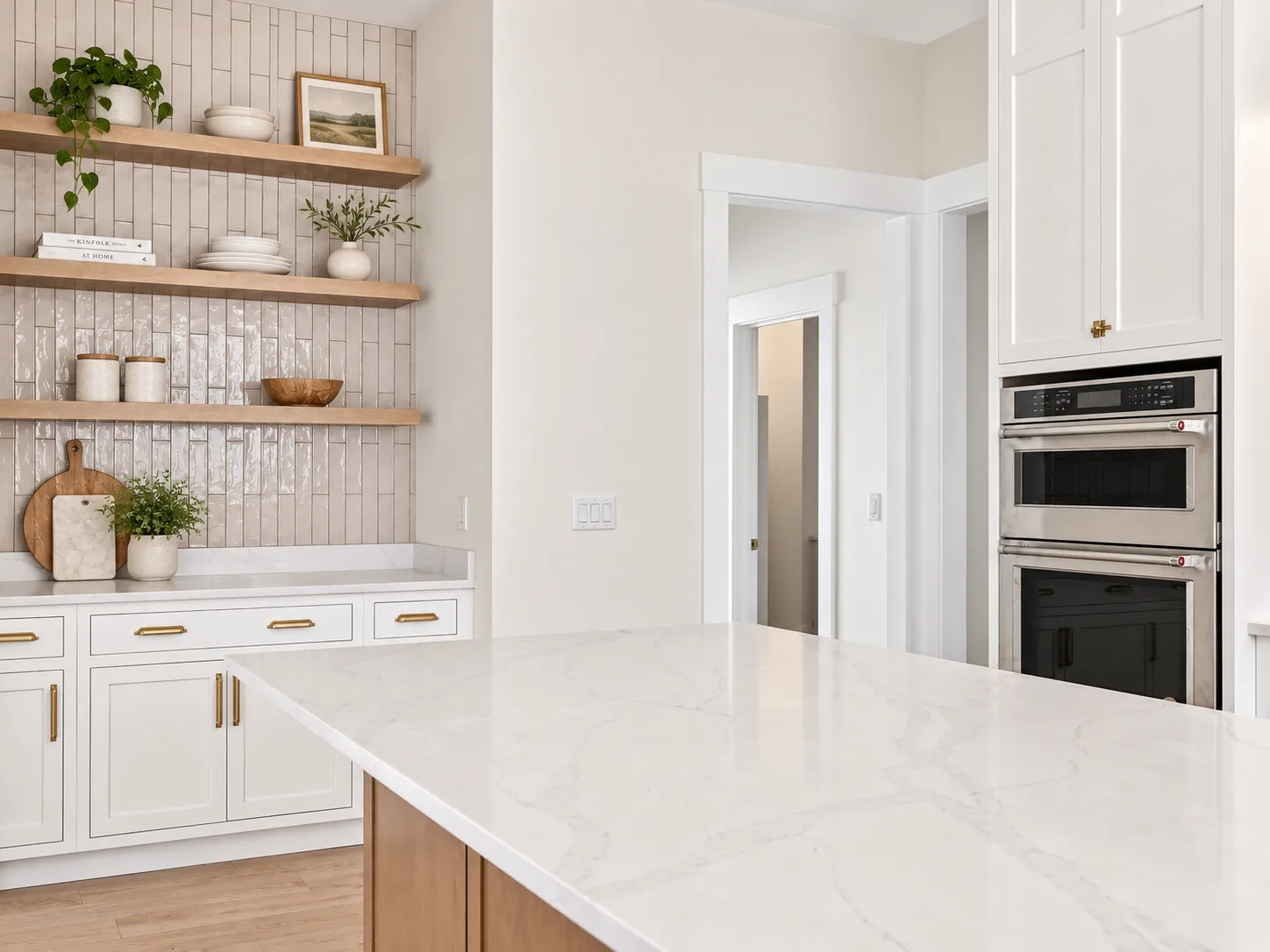 Wall ovens and open shelving beside the island