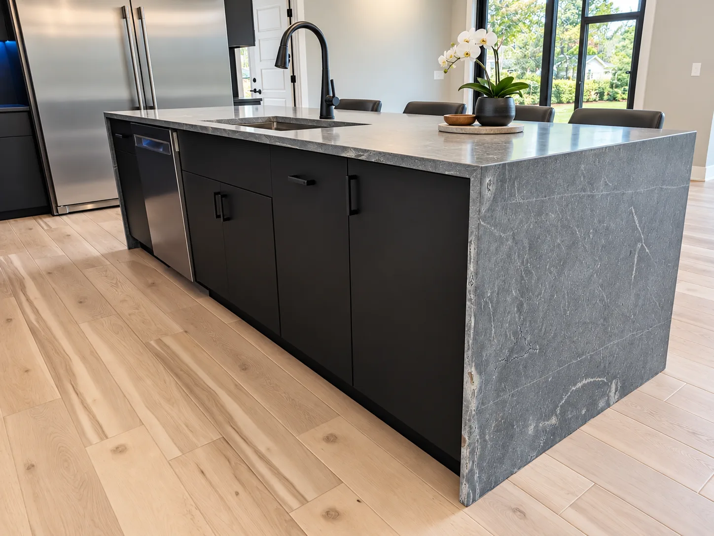 Stone waterfall island against black slab cabinetry