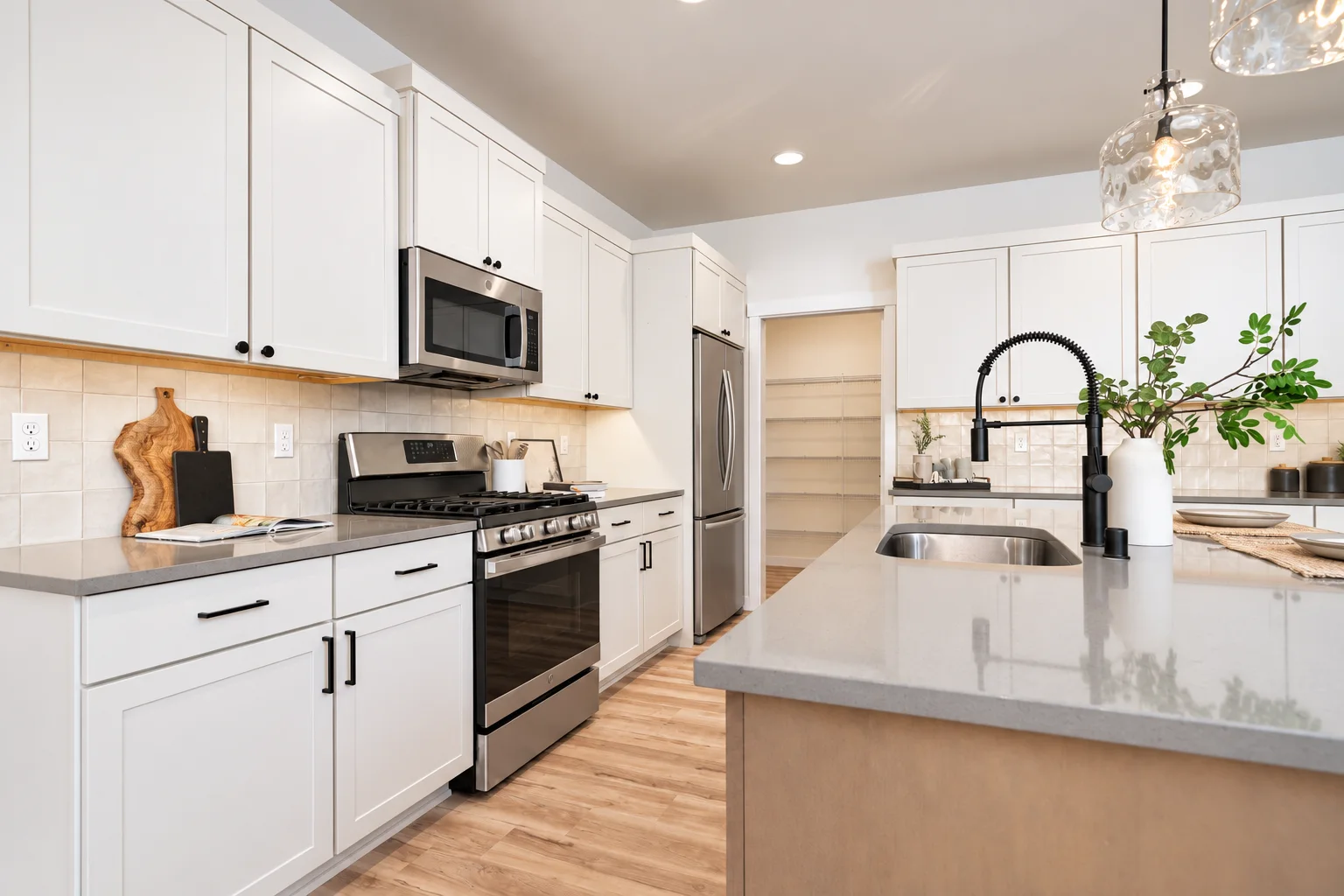 Range wall with gas range, glass pendants and Blond cabinets, northwest Washington spec home