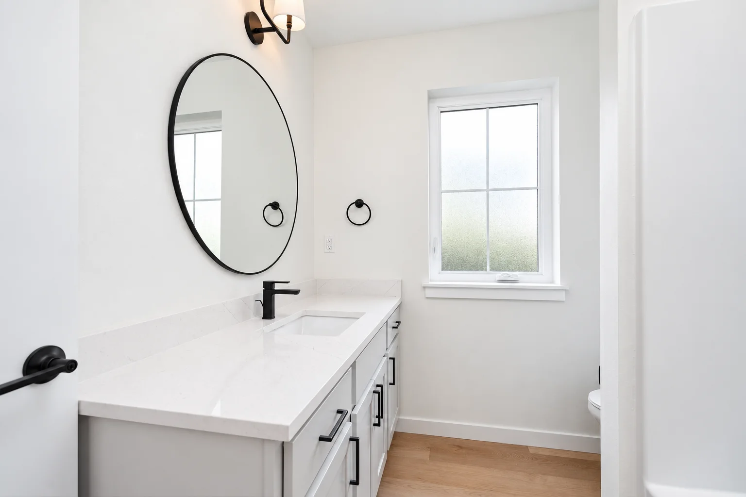 Powder bath vanity in Cloud with round mirror and black accents, northwest Washington spec home