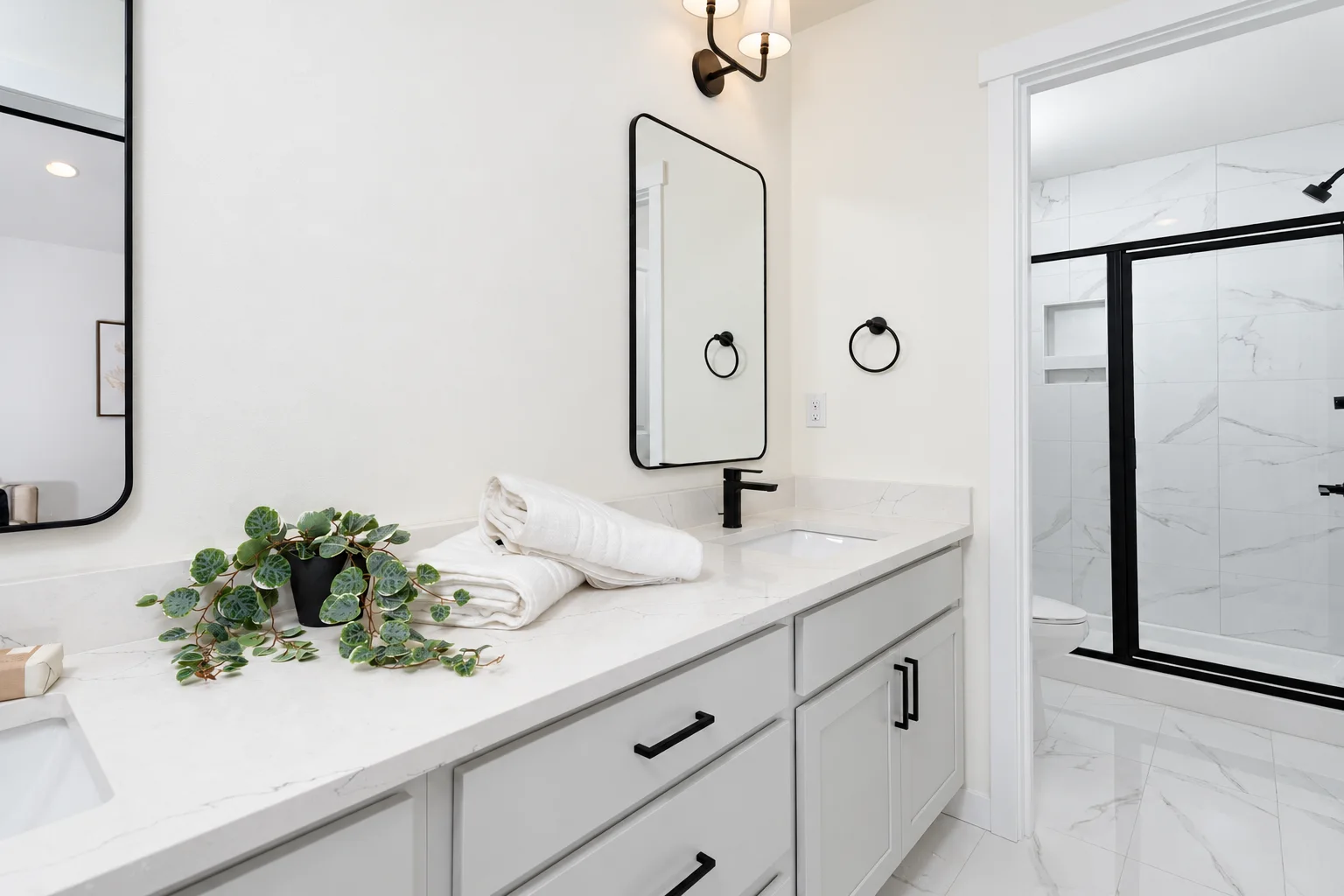 Primary bath vanity in Cloud with black fixtures and marble shower, northwest Washington spec home