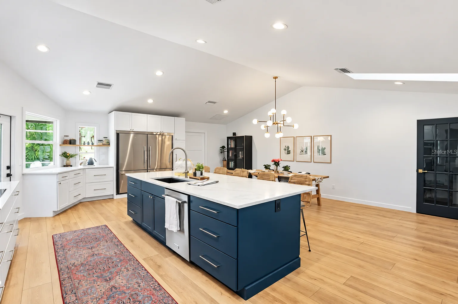 Kitchen fridge run with navy island and runner rug on white oak floors, Sarasota remodel