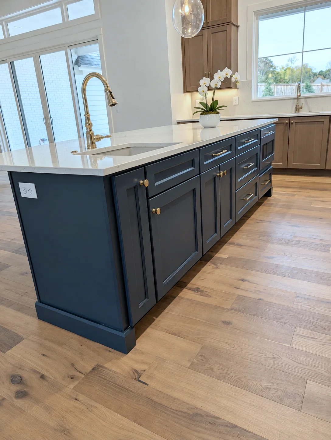 Custom Blue kitchen island with brass faucet and white quartz, cherry cabinets beyond, South Carolina